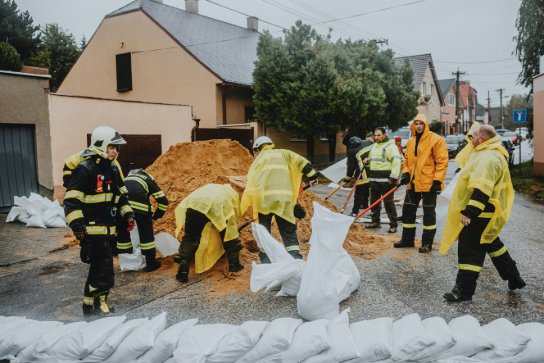 Hulpverleners vullen zandzakken bij een straat met nat weer om overstroming tegen te gaan. (vergroot foto)